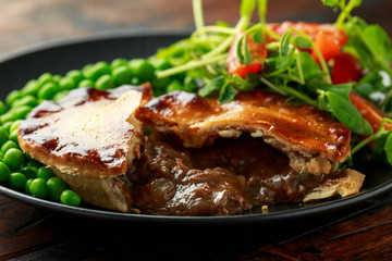 Beef steak pies with rich onion gravy served with sweet peas and salad © grinchh