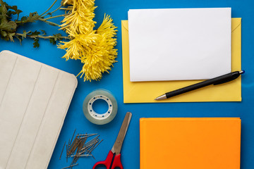Composition Using Yellow Envelope, Blank Paper For Text, Black Pencil, Yellow Flowers, Duct Tape, Scissors, Notebook, and Tablet 