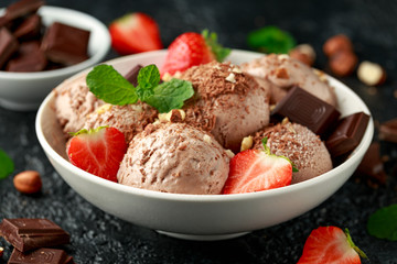 Chocolate Ice Cream with dark chocolate bars, strawberry and hazelnuts in a white bowl