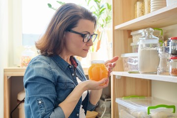 Woman with jar of golden organic fresh honey in the kitchen