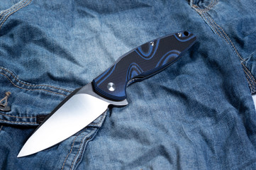 Pocket knife with a blue handle. Knife and jeans.