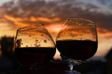 Raise a glass of wine for a well-spent day, weekend. The view of the sunset and the city. Clash of the glasses to make a toast.