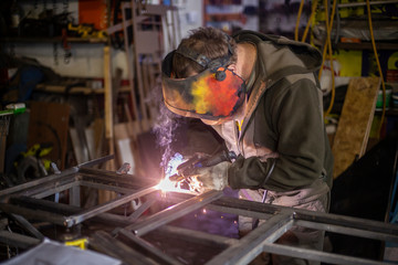 A welder is cooking metal in a protective mask. High temperature of heating.
