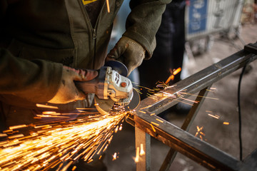 A man processes metal with a grinder.