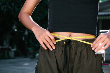 A healthy, fit girl measuring her waist after fitness exercise,Athletic slim woman measuring her...