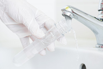 Tap water analysis quality control concept. Hand with a flask and water tap ckose up.
