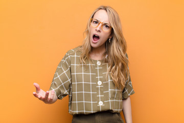 young pretty blonde woman looking angry, annoyed and frustrated screaming wtf or what‚Äôs wrong...