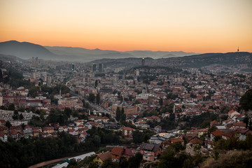 Naklejka premium Arial view of a city from a hill during sunset, Sarajevo Bosnia and Herzegovina. The whole city with mountains layers in the background.