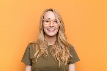 young pretty blonde woman looking happy and pleasantly surprised, excited with a fascinated and...