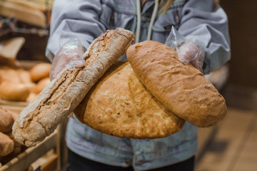 A young woman takes from the counter in the supermarket fresh bread .