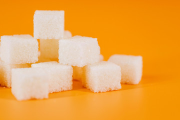 White sugar cubes on yellow background. Cubes of sugar