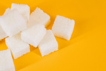 White sugar cubes on yellow background. Cubes of sugar