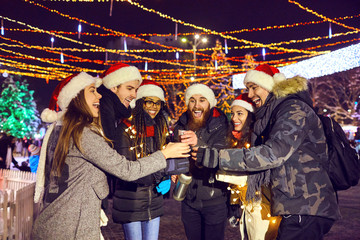 A group of friends drinking hot tea at a fair in Christmas