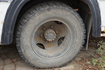 Fototapeta na wymiar big dirty wheel on a truck stands on asphalt