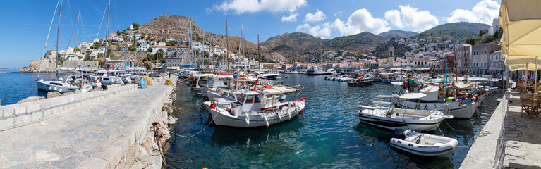 Fototapeta na wymiar Panorama of Boats in the pier with houses and buildings in background in Hydra Island