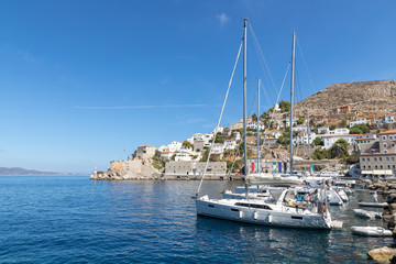 Boats in the pier with houses and buildings in background in Hydra Island