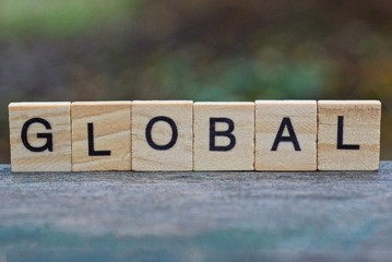 word global made from brown wooden letters lies on a gray wood board