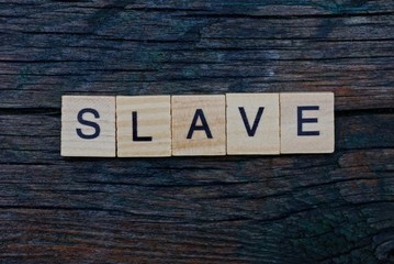 Fototapeta premium word slave made from gray wooden letters lies on a gray table