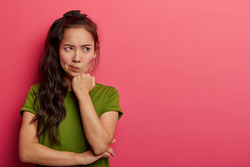 Grumpy displeased Asian female smirks face, keeps hands half crossed, holds chin, has angry...