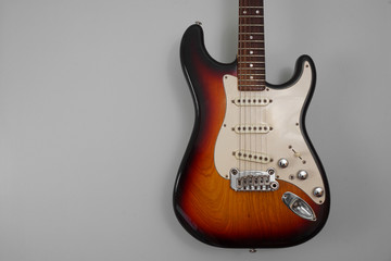 Body of an electric guitar against a grey background