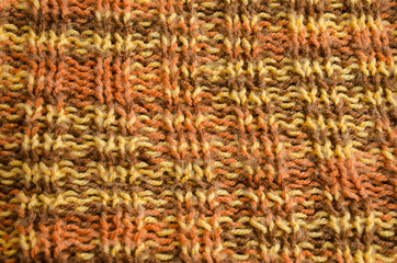 Knitted pattern, warm shades of yarn. Texture of wool product. 