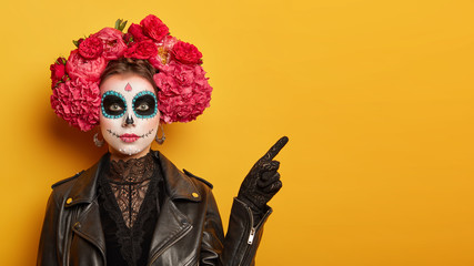 Mexican culture, Day of Death concept. Serious woman with bright scary makeup, flower wreath,...