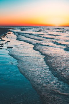 Vertical shot of the wavy ocean at the sunset captured in Vrouwenpolder, Netherlands
