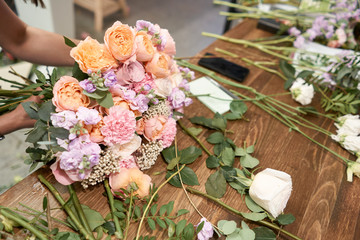 Obraz na płótnie Canvas European floral shop concept. Florist woman creates beautiful bouquet of mixed flowers. Handsome fresh bunch. Education, master class and floristry courses. Flowers delivery.