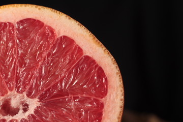 part of sliced grapefruit in full dark under studio lighting