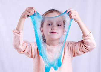 Adorable little girl holding slime toy, worldwide popular self made toy. Kid playing with slime...
