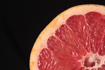 part of sliced grapefruit in full dark under studio lighting
