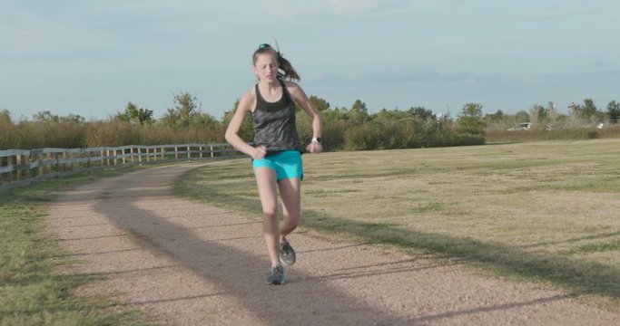 A teenage girl long distant runner starts to limp during training and her coach or father comes into the scene to check out the problem.