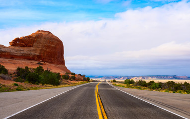 The road passing through the prairie against the backdrop of a mountain landscape.