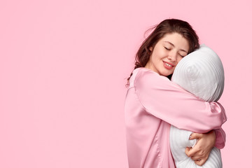 Tender female in sleepwear embracing pillow