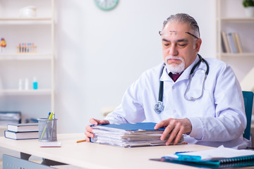 Old male doctor working in the clinic