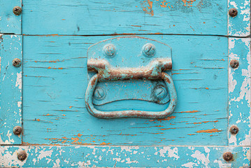 Blue painted steel handle on old weathered wooden box.