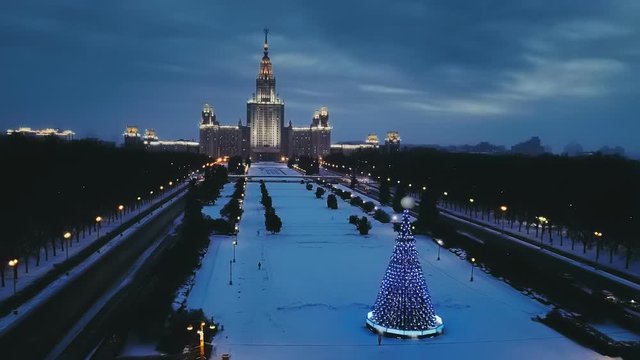 Glowing in the night the main building of Moscow State University (MGU) in the New Year and a luminous by garlands large Christmas tree nearby. Copter ( drone ) shooting