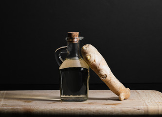 Ginger oil bottle with ginger root on wooden cutting board. Healthy eating concept.