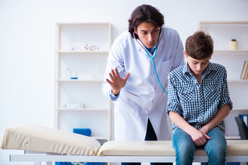 Male doctor examining boy by stethoscope