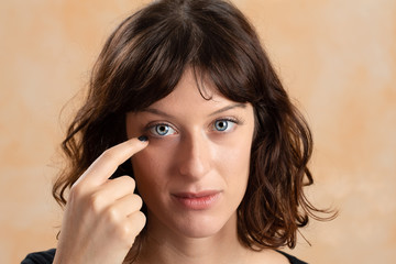 Girl with a finger near the eye to arrange contact lenses. Concept of vision with lenses and vision...