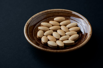 Vitamin C tablets on dark  paper background. Close up. 