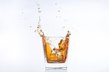 Whiskey and ice. Rum with ice. Brown brandy with splashes. Ice cube falls into a glass with splashes
