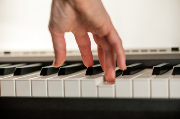 Male hand plays the piano keyboard isolated on white background. Close-up shallow depth of focus of the part. Rear view from below. Mechanics of the movement of keys are clearly visible.