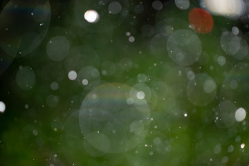 Abstract falling snow or rain bokeh texture overlay on green background.