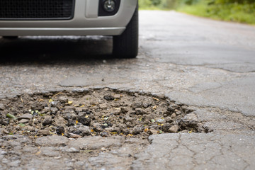 Damaged road full of cracked potholes in pavement