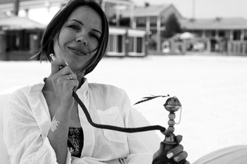 woman with a hookah on the beach smokes marijuana