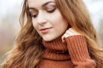 Beautiful young girl in a brown sweater. Close-up. The concept of autumn, cosmetics and makeup.