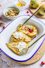 Sweet baked pears with honey, nuts, cranberries and cinnamon in enameled baking bowl on stone background. Top view. Flat lay
