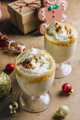 New Year or Christmas Eggnog cocktail - hot winter or autumn drink with milk, eggs and dark rum, sprinkled with cinnamon and nutmeg in a glass on wooden background, festive decoration