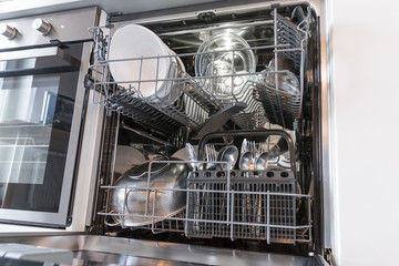 Open dishwasher with clean dishes in a white kitchen